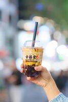 woman hand holding brown sugar boba milk tea with tapioca pearls, Xing Fu Tang brand known for making the best hand crafted brown sugar boba. Ximending Night market, Taipei, Taiwan, 02 April 2023 photo