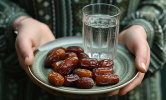 AI generated Hands holding plate of dates and glass of water, islamic traditional clothing photo