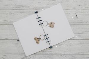 Notebook with rings, checkered sheets, keychain with a car and a house. photo