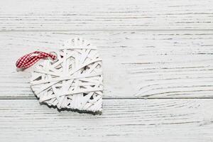 Decorative white vine heart, toy for decoration on a wooden background photo