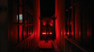 Silhouette of a person in a dark corridor with ominous red lighting, creating a suspenseful atmosphere. video