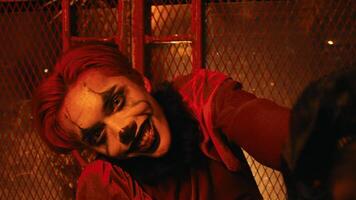 un' raccapricciante clown con rosso capelli e costume pose e balli nel un' frequentato capanna quello luci su rosso video