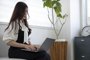 un trabajando japonés mujer por remoto trabajo en el hogar oficina de cerca foto