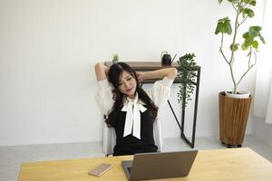 un relajado japonés mujer por remoto trabajo en el pequeño oficina foto