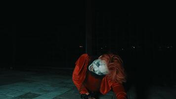 une homme dans une rouge costume et pitre maquillage des rires tandis que posant dans une très terrifiant pose, pendant Halloween video