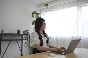 un japonés mujer comprobación teléfono inteligente por remoto trabajo en el hogar oficina foto