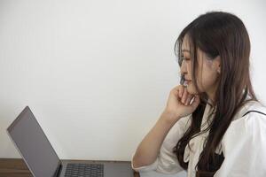 un trabajando japonés mujer por remoto trabajo en el hogar oficina de cerca foto