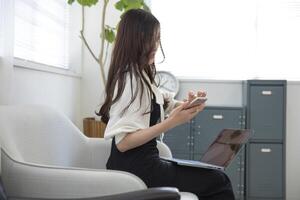 A Japanese woman checking smartphone by remote work in the small office photo