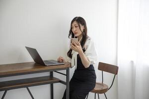 A Japanese woman checking smartphone by remote work in the home office photo