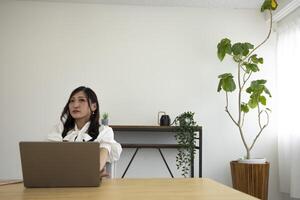 un relajado japonés mujer por remoto trabajo en el pequeño oficina foto