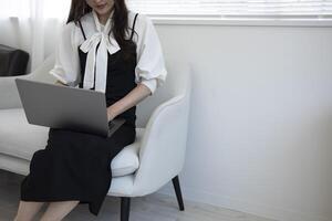 un japonés mujer mecanografía ordenador portátil por remoto trabajo en el oficina sin rostro composición foto