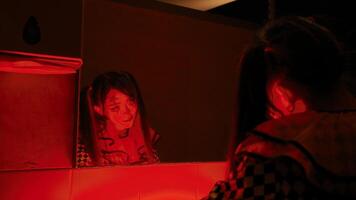 Person in red light looking at reflection in mirror, covering face with hand, conveying emotion or introspection. video