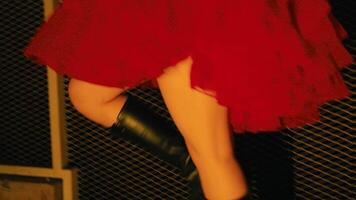 Close-up of a woman's legs in black boots and a red skirt, with a moody, dark background. video