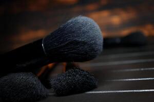 A few makeup brushes lie on a black wooden table. selective focus.High quality photo