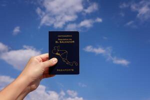 el mano de un invisible persona sostiene el pasaporte de el el Salvador en contra el cielo con nubes alto calidad foto