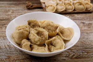 plate of homemade dumplings, and not boiled standing on the board. selective focus . photo