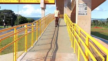 brasilia, Brasil, febrero, 14 2024 hombre caminando abajo el rampa de un recién construido elevado peatonal pasarela en noroeste brasilia video