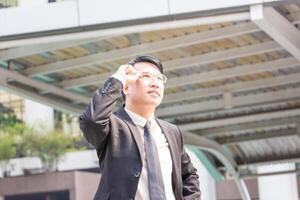 Asia businessman standing outdoors and looking at the sky photo