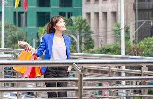 Young Asian woman carrying shopping bags while walking along the street. Shopping concepts photo