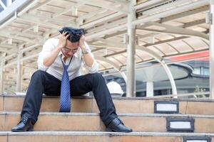 Lonely man lost in a depression sitting on the stairs, Serious engineer man in construction site, feeling sad concepts photo