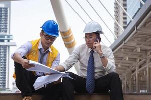 ingeniero hombre equipo con dibujo papel planificación proyectos en construcción sitio foto