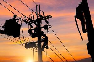 Silhouette of Electrician officer team climbs a pole and using a cable car to maintain a high voltage line system, Electrician lineman worker at climbing work on electric post power pole photo