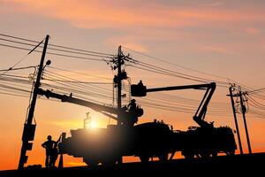 Silhouette of Electrician officer climbs a pole and uses a cable car to maintain a high voltage line system, Shadow of Electrician lineman repairman worker at climbing work on electric post power pole photo