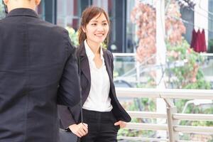 Smiling Asian urban business woman walking outside office photo