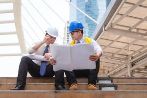 Engineer and foreman worker team with blueprint paper planning projects on construction site photo