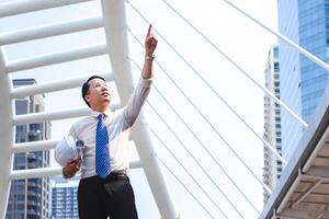 Business engineer man looking plan on site, Architect pointing at construction site photo