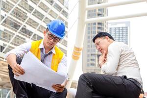 Engineer and foreman worker checking project at building site, Engineer and builders in hardhats discussing on construction site photo