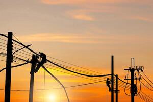 silueta de electricista guardavía trabajador a alpinismo trabajo en el eléctrico enviar poder polo, electricista comprobación Encendiendo a el LED calle lámpara enviar foto