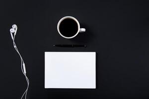 Black office desk white mockup notebook, pen, headphones and a cup of coffee. Top view with copy space for text input. High quality photo