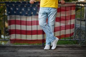 male legs in torn jeans on a background of fabric with a print of the American flag. photo