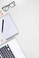 light office desk with laptop, white notebook mockup and glasses . Top view with copy space for text input. High quality photo. photo