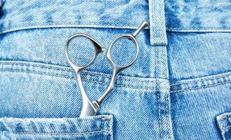 professional hairdressing scissors lie in the back pocket of jeans .High quality photo