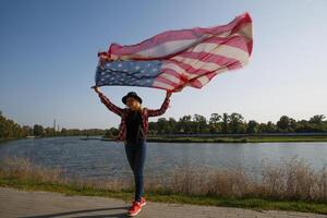 a young girl holding a scarf with a pattern of American flag waving in the wind. High quality photo