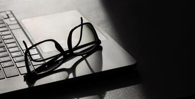 shadow falls on an open laptop on which reading glasses lie. selective focus photo