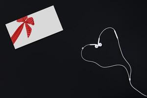 Greeting cards and white heart-shaped headphones lie on a black surface. Congratulations on the holiday. photo