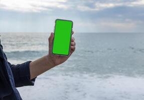 manos de un hombre señalando su dedo a un móvil teléfono con un blanco verde pantalla. alto calidad foto