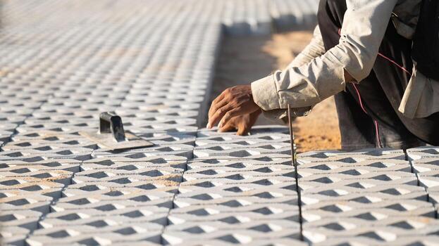 instalando pavimentación bloques concepto. diligente hombre se involucra en al aire libre construcción trabajar, laboriosamente instalando pavimentación bloques y cemento a crear un durable y bien elaborado piso en construcción sitio foto