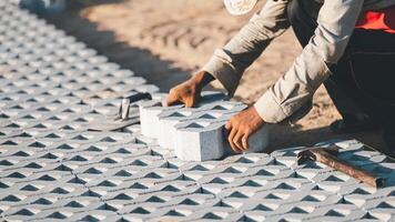 Installing paving blocks concept. Diligent man engages in outdoor construction work, laboriously installing paving blocks and cement to create a durable and well-crafted floor on construction site photo