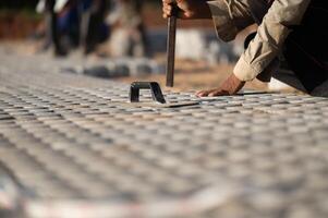 Installing paving blocks concept. Diligent man engages in outdoor construction work, laboriously installing paving blocks and cement to create a durable and well-crafted floor on construction site photo