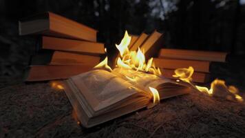un Aperto libro è su fuoco. grande luminosa fiamma, ardente carta su vecchio pubblicazione nel il scuro. libro ardente - censura concetto, lento movimento, avvicinamento, 4k video