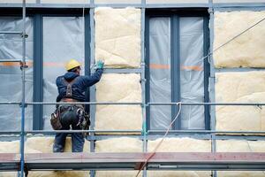 AI Generated Worker applies insulation with glass wool for energy saving on a new construction site. Generative AI photo