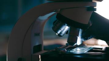 Microscope Analysis in Progress,Gloved hand adjusting microscope with slide in a research lab setting. video