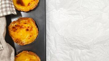 Lots of freshly baked Pastel de nata or Portuguese egg tart desserts in a baking dish. Pastel de Belme is a small pie with a crispy puff pastry crust and a custard filling. Small cupcake. photo