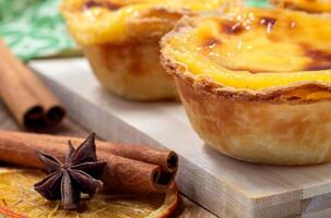 Lots of desserts Pastel de nata or Portuguese egg tart and cinnamon sticks. Pastel de Belm is a small pie with a crispy puff pastry crust and a custard cream filling. photo