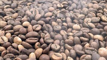 Freshly roasted hot coffee beans in smoke can be used as a background. Top view of aromatic brown coffee beans scattered on the surface. photo