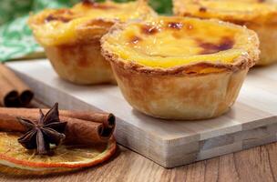 Lots of desserts Pastel de nata or Portuguese egg tart and cinnamon sticks. Pastel de Belm is a small pie with a crispy puff pastry crust and a custard cream filling. photo